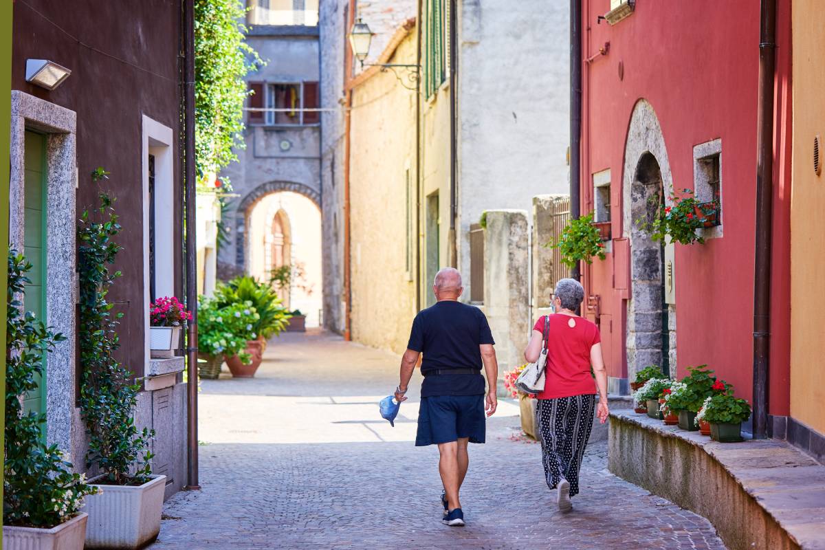 Older couple walking through colourful Europe street budget senior travel